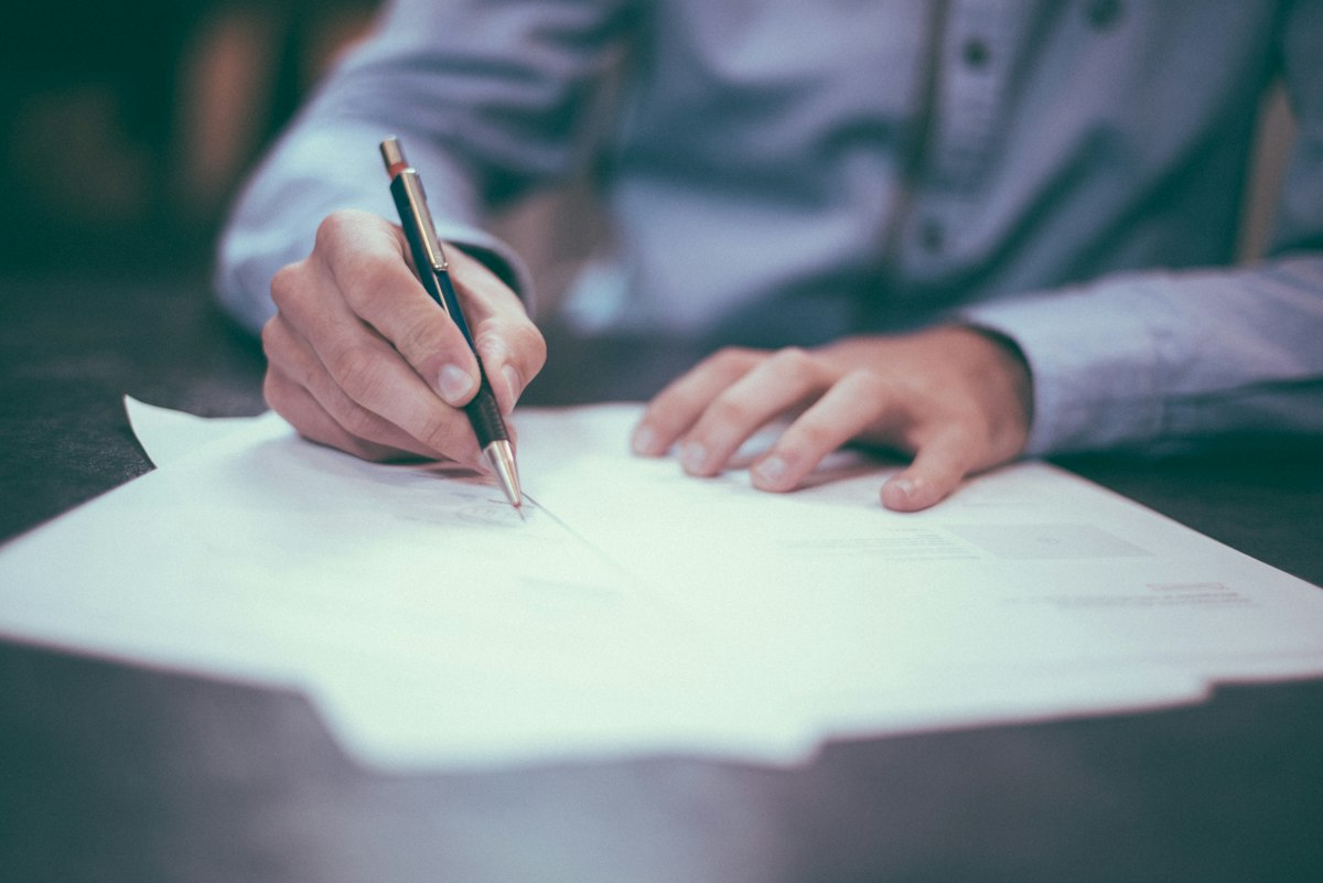 Hands signing a document